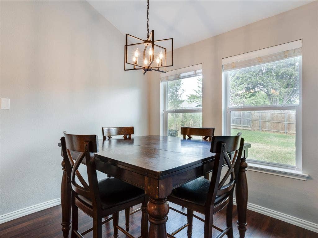 Geometric metal chandelier fixture, wood-finish flooring, and large windows with natural light