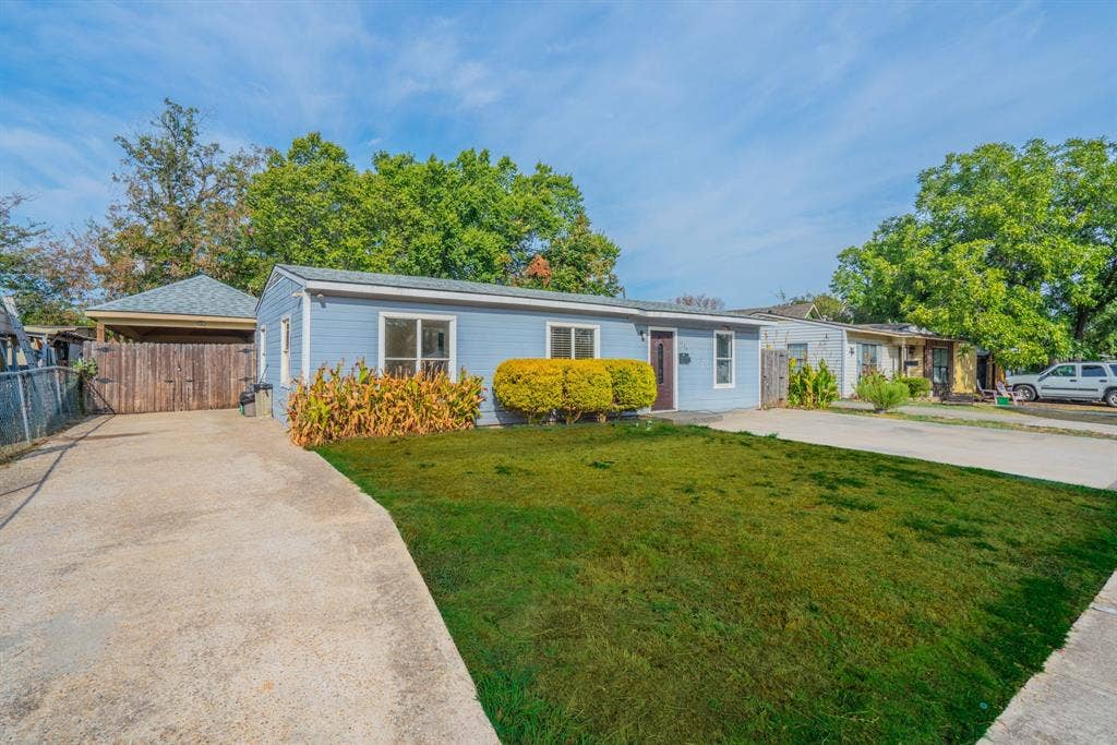 934 Indian Hills Drive, Grand Prairie, TX 75051 Light blue exterior siding, white window trim, front lawn, concrete driveway, and covered carport with wood fencing