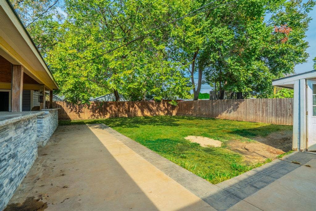 934 Indian Hills Drive, Grand Prairie, TX 75051 Expansive backyard featuring a manicured lawn, established trees, wood fencing, and a concrete patio
