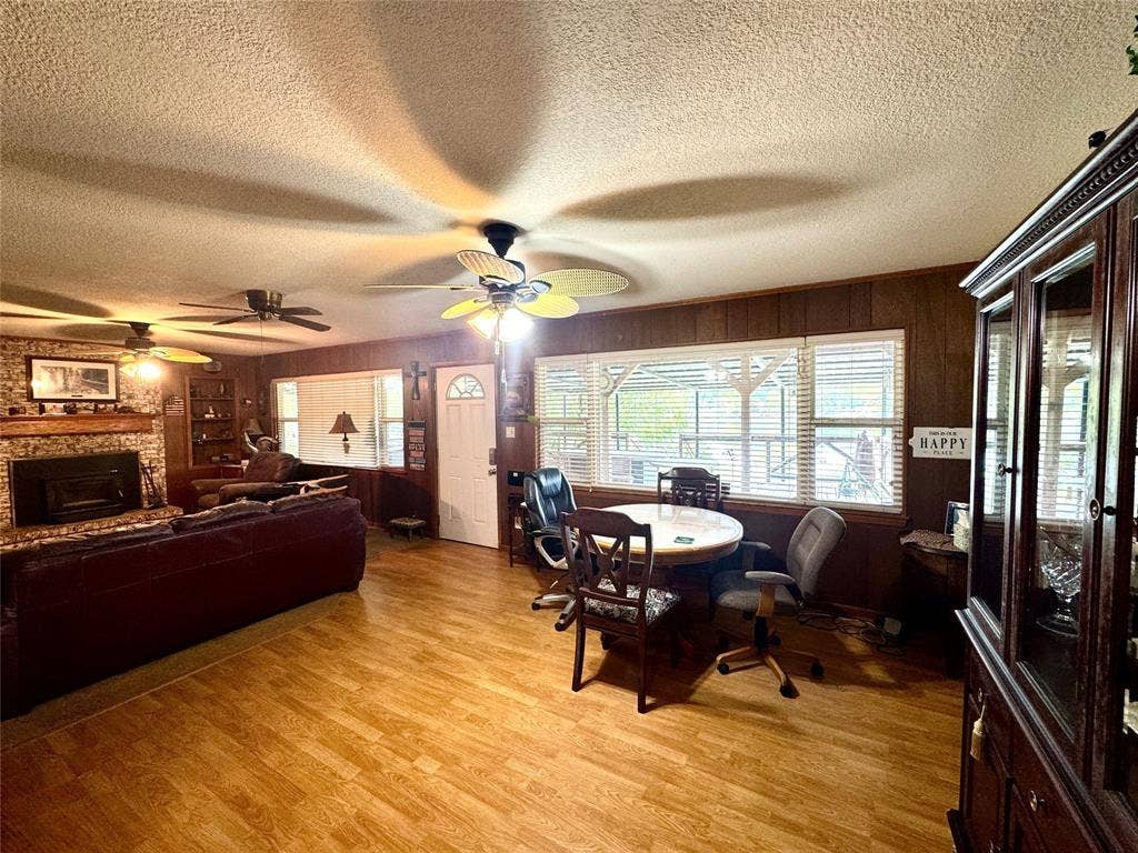 10122 Ash Cove, Wills Point, TX 75169 Wood-finish flooring, wood paneling, multiple ceiling fans, and a brick-surround fireplace with a hearth