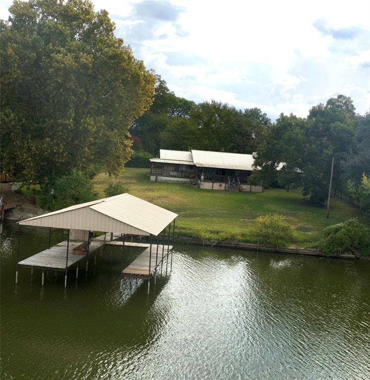 10122 Ash Cove, Wills Point, TX 75169 Waterfront property featuring a private boat dock with covered slip, expansive green space, and mature trees