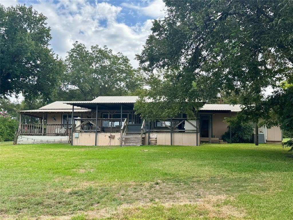 10122 Ash Cove, Wills Point, TX 75169 Expansive green lawn with mature trees and a multi-level deck featuring a wood railing