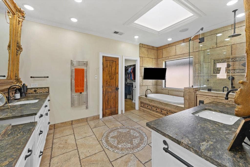 1312 Chippewa Drive, Plano, TX 75093 Heated travertine floors, dual vanities and a towel warmer add comfort to the primary bath.