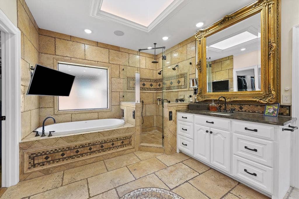 1312 Chippewa Drive, Plano, TX 75093 Skylit primary bath with a deep soaking tub, Kohler digitally controlled shower and large television.