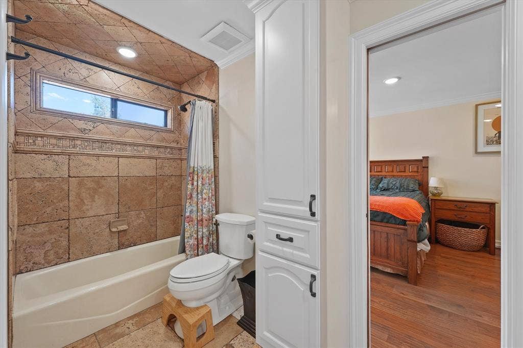 1312 Chippewa Drive, Plano, TX 75093 Upstairs bath with a tub/shower combination and custom travertine tilework.