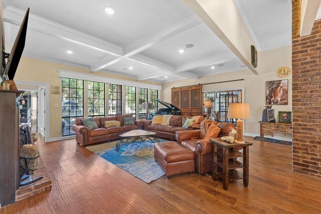 1312 Chippewa Drive, Plano, TX 75093 Spacious living room with a wood-burning fireplace and wide-plank hand-scraped white oak floors.