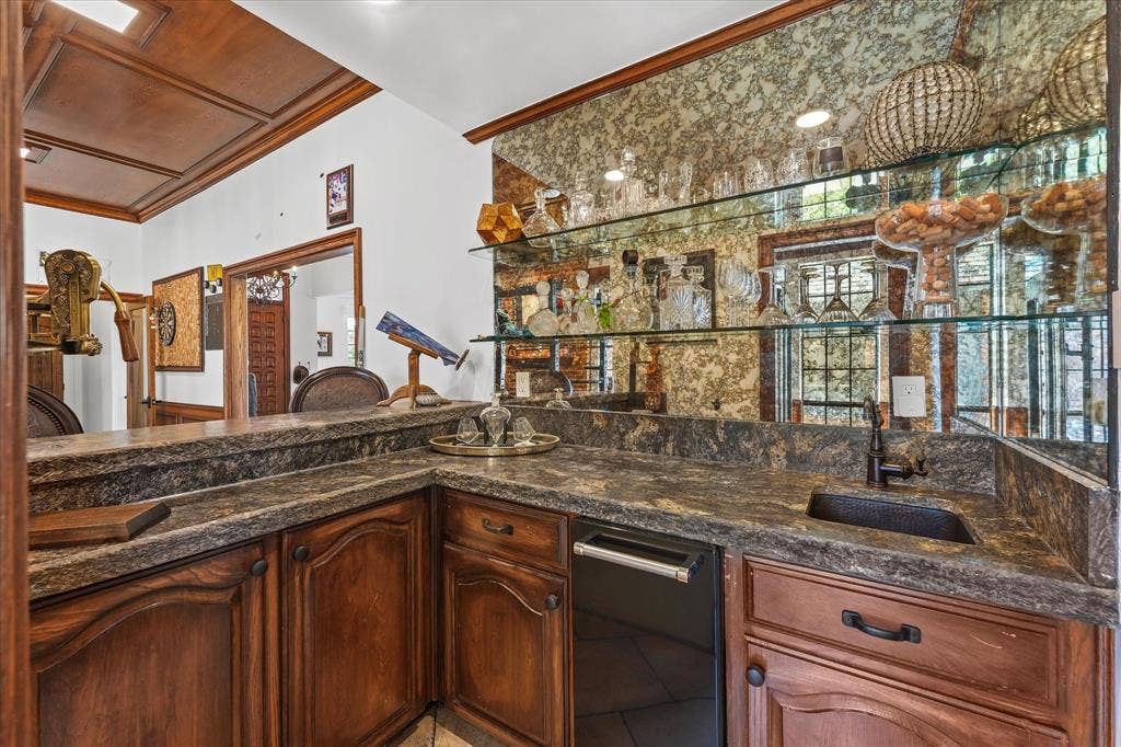 1312 Chippewa Drive, Plano, TX 75093 Custom wet bar with a smoked mirror, floating glass shelves, ice maker and a hammered copper sink.