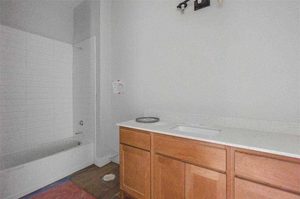 1312 Tahonta Drive, Hewitt, TX 76643 Bathtub with white subway tile surround, vanity with light wood-finish cabinetry, integrated sink, and light-toned countertop