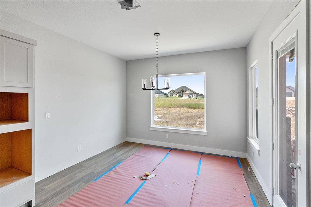 1312 Tahonta Drive, Hewitt, TX 76643 Wood-finish flooring, built-in cabinetry with open shelving, single-pane windows, and a multi-bulb chandelier