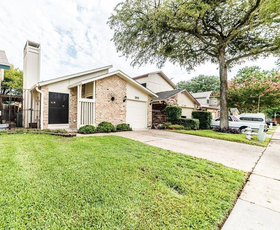 2915 Canis Circle, Garland, TX 75044 Brick exterior with a prominent, tall chimney structure, attached garage, and a sloped roofline