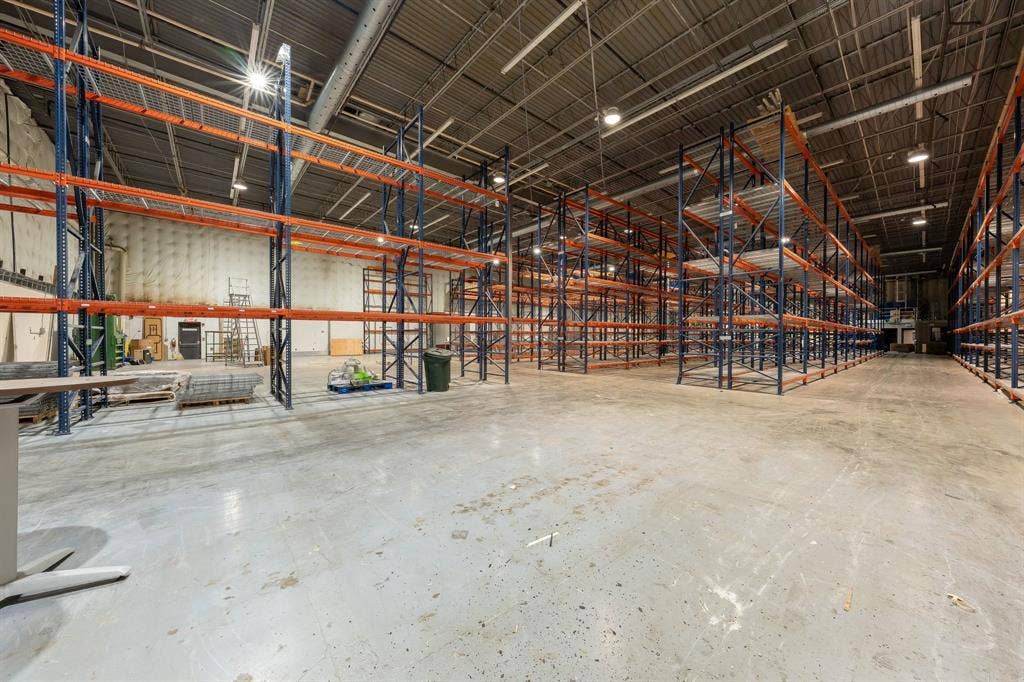 1701 W Walnut Hill Lane, #100, Irving, TX 75038 High-bay warehouse space featuring metal racking systems, concrete flooring, and overhead lighting
