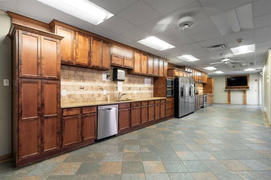 1701 W Walnut Hill Lane, #100, Irving, TX 75038 Expansive kitchen space featuring abundant wood cabinetry, integrated stainless steel appliances, granite countertops, a tiled backsplash, and durable tile flooring