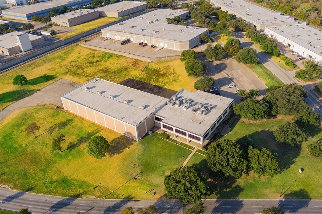 1701 W Walnut Hill Lane, #100, Irving, TX 75038 Industrial building with a tan facade, multiple windows, and extensive surrounding green space