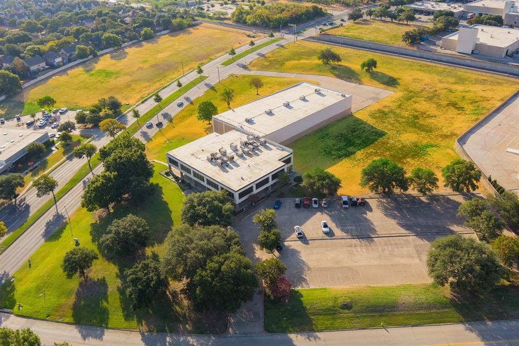 1701 W Walnut Hill Lane, #100, Irving, TX 75038 Expansive commercial property featuring two structures, paved parking areas, and surrounding green spaces
