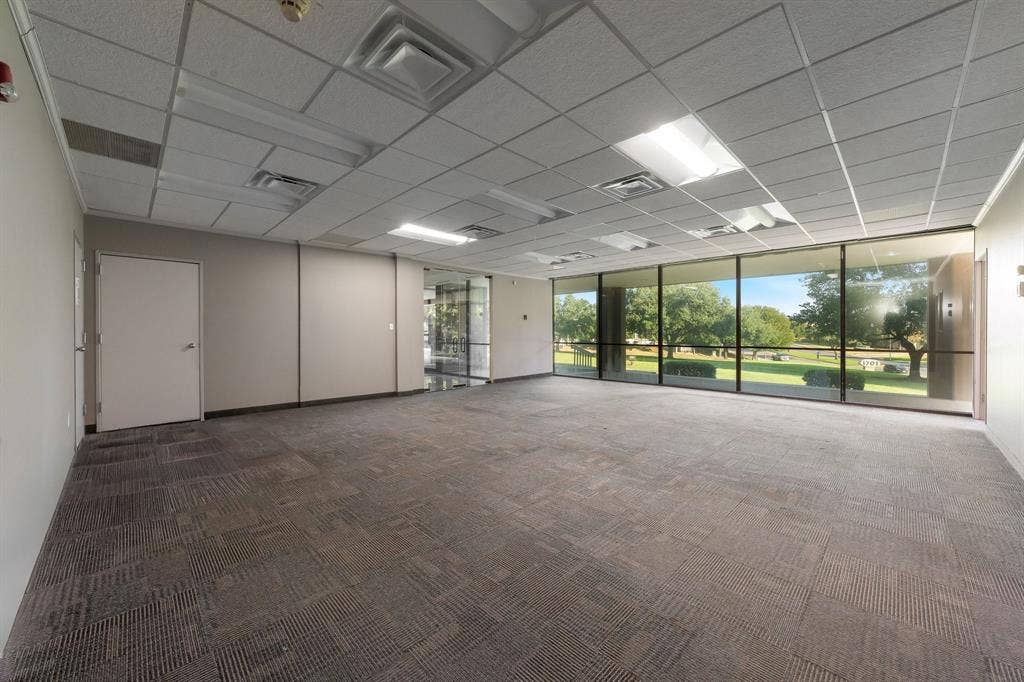 1701 W Walnut Hill Lane, #100, Irving, TX 75038 Expansive commercial space featuring wall-to-wall carpeting, a grid-pattern drop ceiling, recessed lighting, and large windows with exterior green space