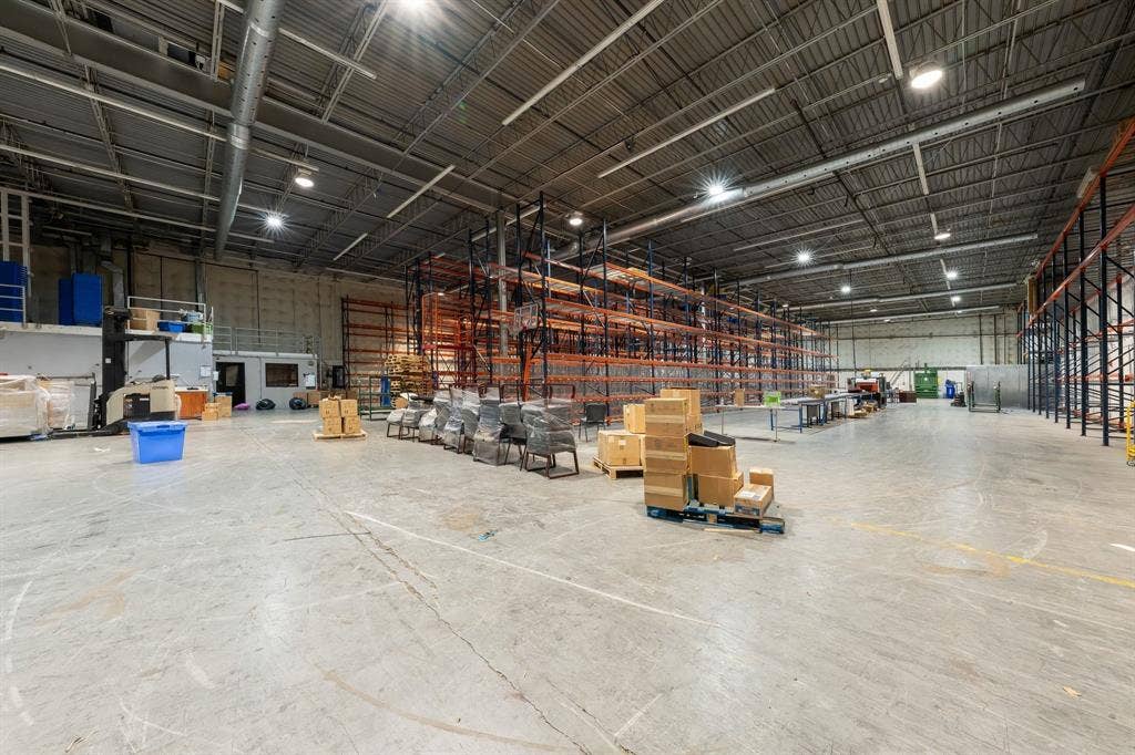 1701 W Walnut Hill Lane, #100, Irving, TX 75038 Spacious industrial facility with a concrete floor, high ceilings, exposed ductwork, and fluorescent lighting