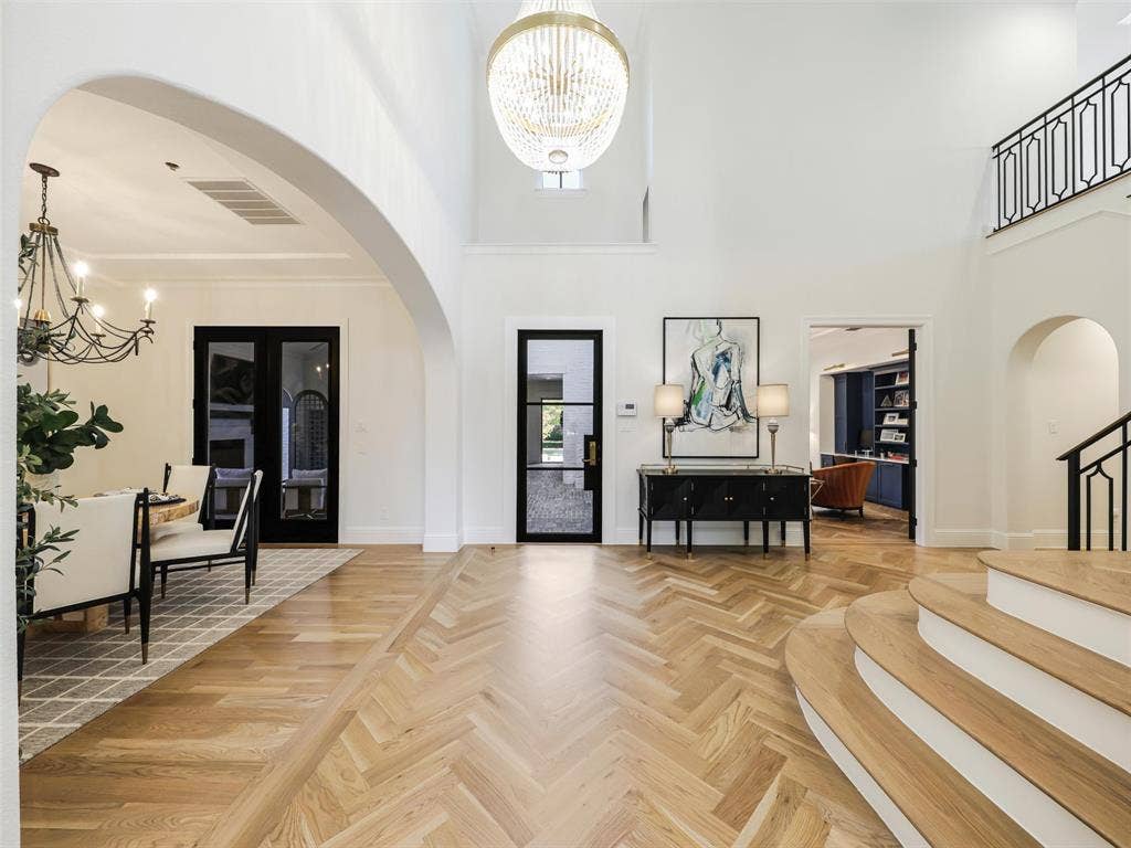 12313 Winding Hollow Lane, Frisco, TX 75033 Main floor 2,728 sqft The experience begins at the formal entry, where soaring architecture immediately sets the tone for the home. A cathedral ceiling, statement chandelier, and striking herringbone-pattern white oak hardwood flooring create a memorable first impression. Black iron doors installed in 2023 add architectural character, while premium Visual Comfort lighting, upgraded luxury hardware, extensive custom cabinetry, and thoughtfully designed built-ins continue throughout the residence. Wide-plank white oak flooring flows through the main living areas, bringing warmth and continuity to the sophisticated interior.