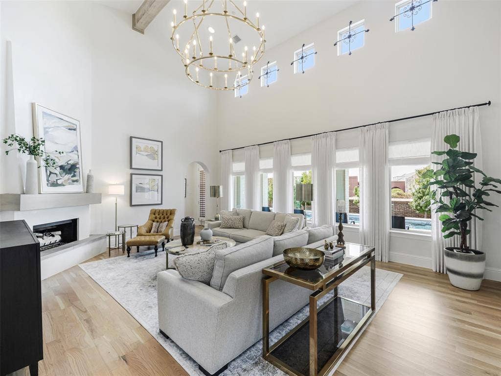 12313 Winding Hollow Lane, Frisco, TX 75033 The family room which is open to the kitchen, has a corner fireplace and floor to ceiling windows that overlook the back patio. Sonos speakers in the family room are included, as are 12 flatscreen TVs throughout the home. Visual Comfort Chapman Myers Daralana Oversized two tier chandelier in antique burnished brass.