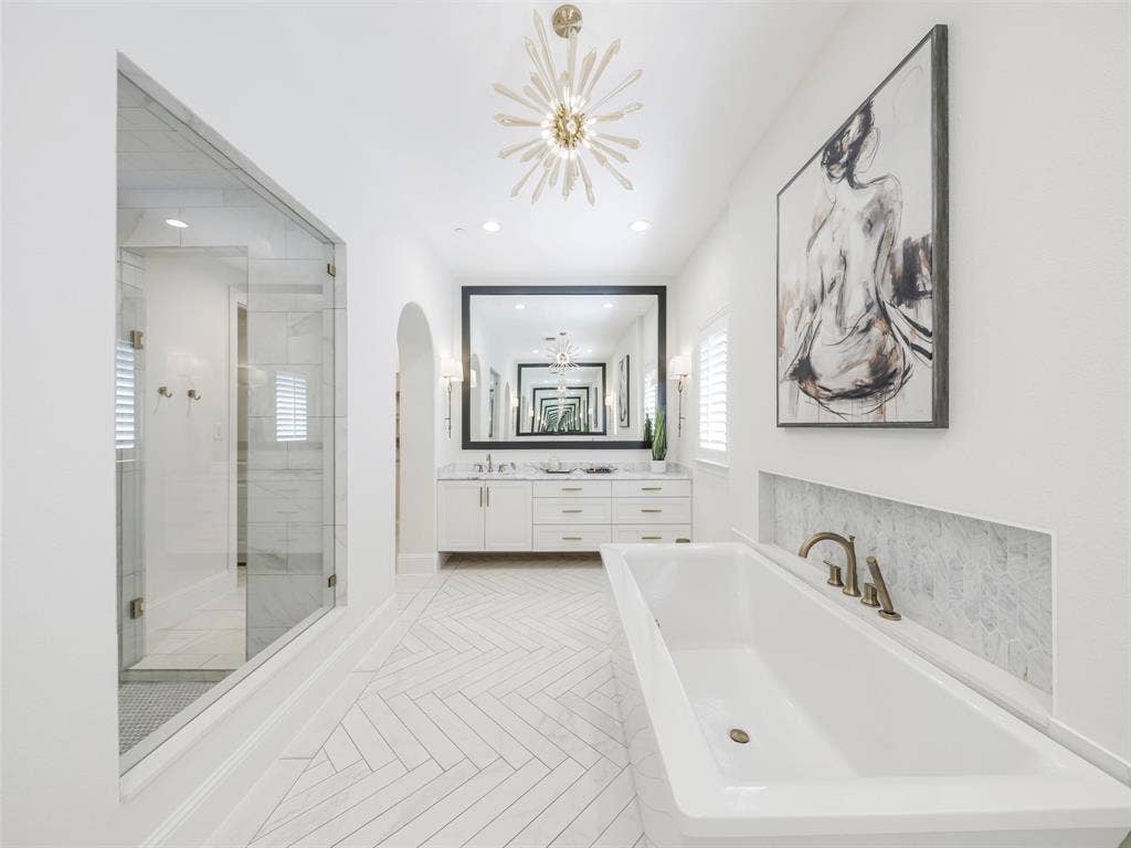 12313 Winding Hollow Lane, Frisco, TX 75033 Custom white oak double doors introduce a beautifully designed retreat that continues into a spa-inspired ensuite bath. High-end finishes include Fumo marble countertops, oversized custom mirrors, a generous 72-by-36-inch soaking tub, Delta faucets, rain shower, body spray jets, and tub faucet. The combination of natural stone, designer fixtures, and generous proportions creates the feeling of a private luxury spa within the home.Storage is equally impressive with a spacious 12-by-11-foot primary walk-in closet. Direct access from the primary suite area to the laundry room adds an exceptionally practical feature to the floor plan.