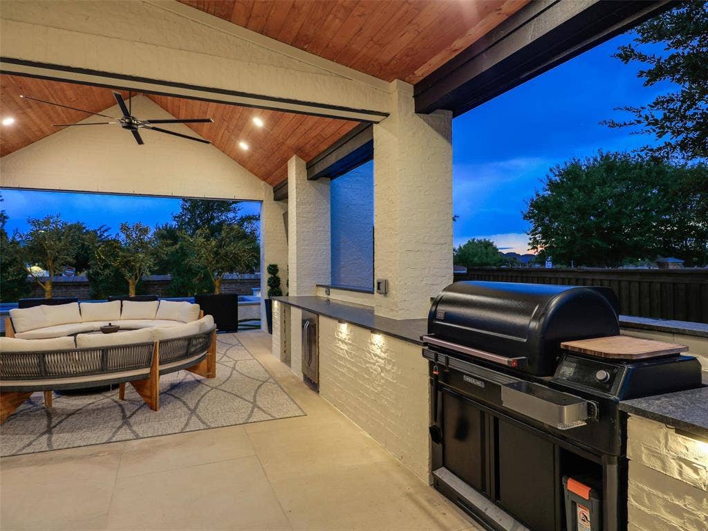 12313 Winding Hollow Lane, Frisco, TX 75033 Back Patio 9x28: Nearby, the outdoor kitchen makes hosting effortless. Steel Grey granite countertops with a sophisticated leathered finish provide both durability and visual appeal. A Traeger Timberline XL Wi-Fi pellet grill, added in 2023, provides an outstanding setup for grilling, smoking, and preparing meals outdoors. From weekend barbecues and pool parties to relaxed evenings by the fireplace, this backyard was created for enjoying the North Texas lifestyle.