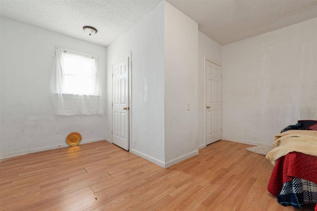 Wood-finish flooring, white walls, white paneled doors, and an overhead flush-mount light fixture
