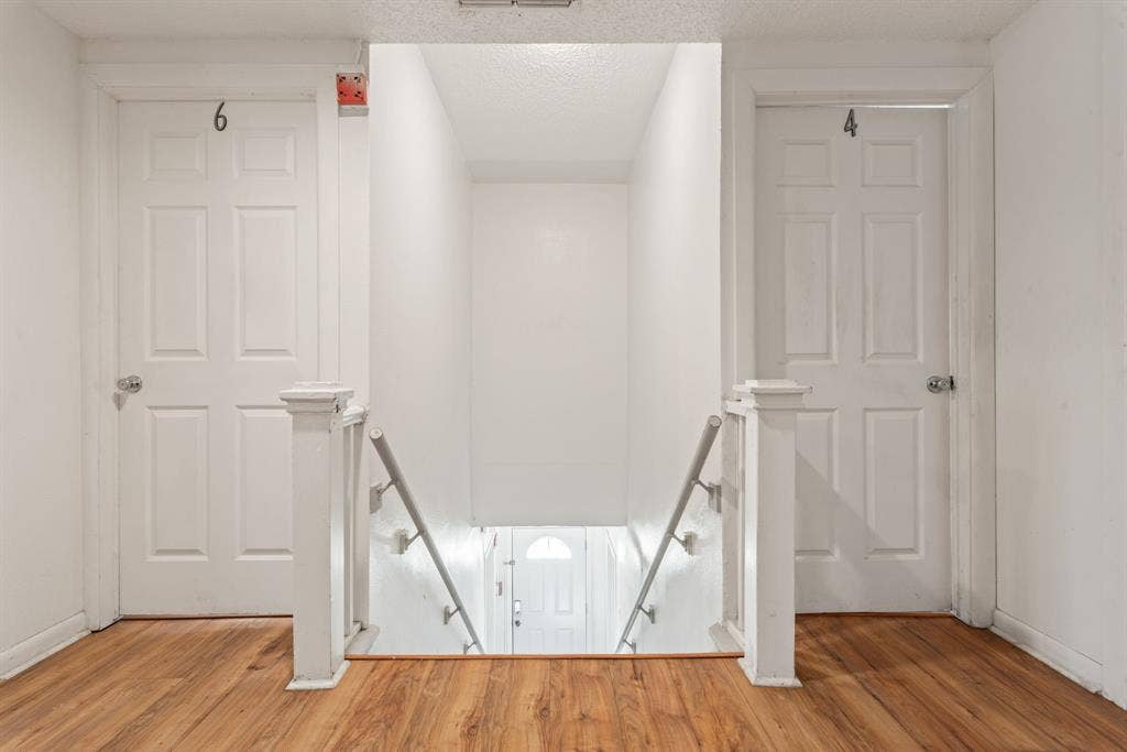 Wood-finish flooring, white paneled doors with chrome hardware, and white painted walls