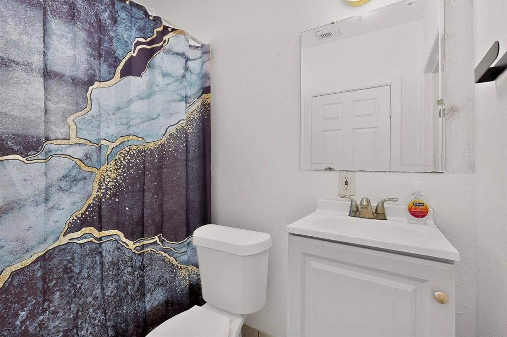 White vanity with integrated sink, wall-mounted mirror, and a two-door cabinet