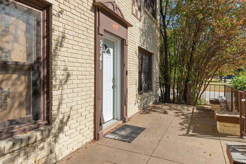 Brick exterior with a white entry door, framed by a decorative brown door surround