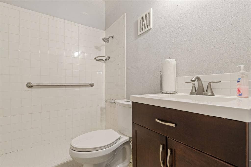 White tiled shower surround with grab bar