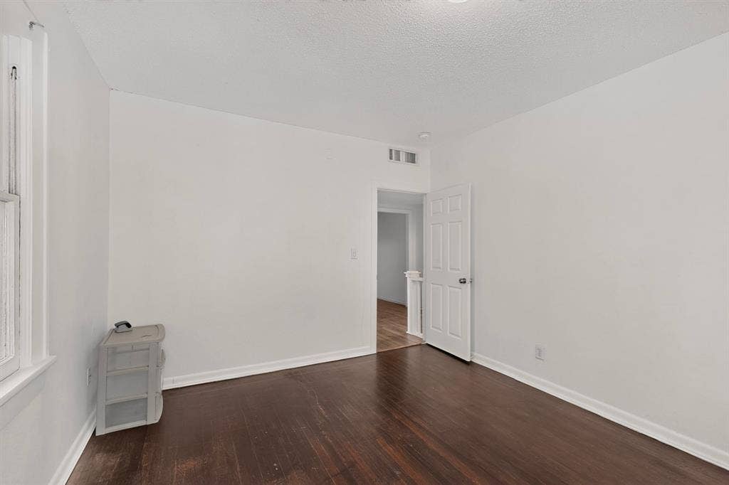 Hardwood flooring, painted white walls, recessed lighting, and a white interior door