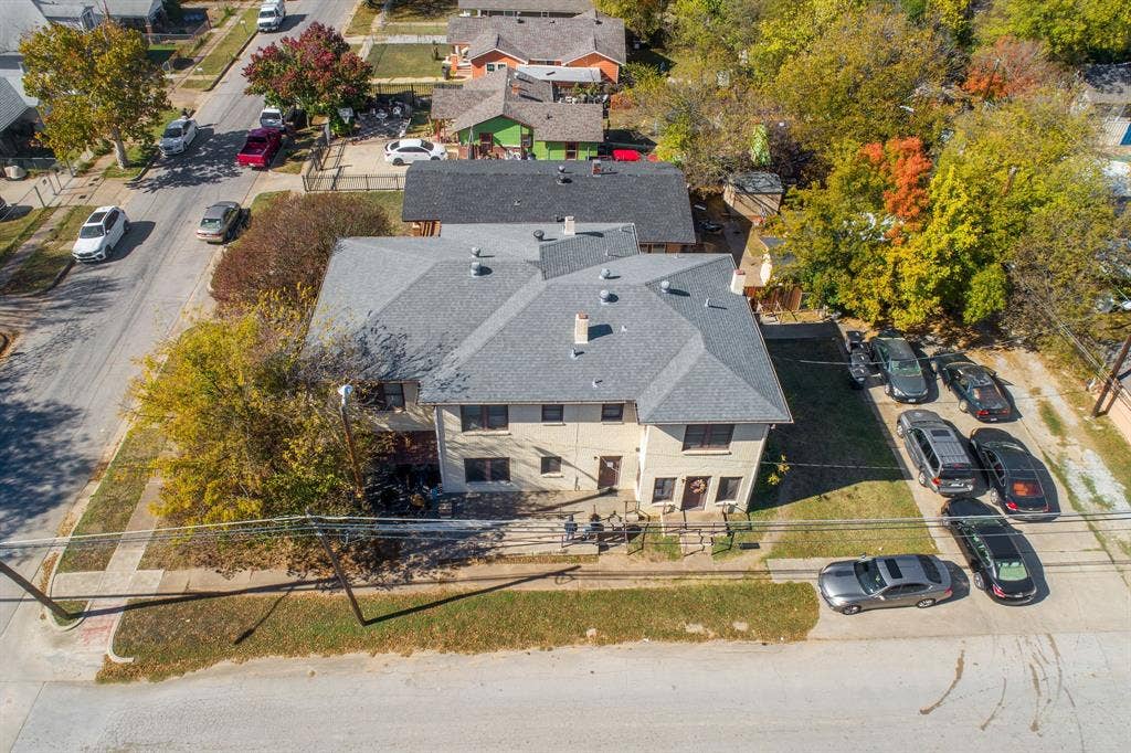 Two-story exterior with a gray shingle roof, paved driveway, and established trees