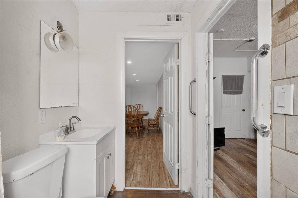 White vanity with integrated sink, chrome faucet, and white toilet