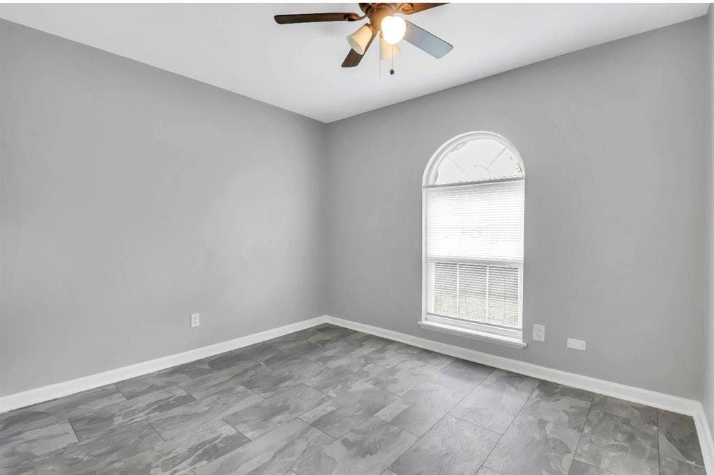 1509 California Trail, Grand Prairie, TX 75052 Room featuring a prominent arched window, grey wall paint, wood-finish flooring, white baseboards, and a ceiling fan with integrated lighting