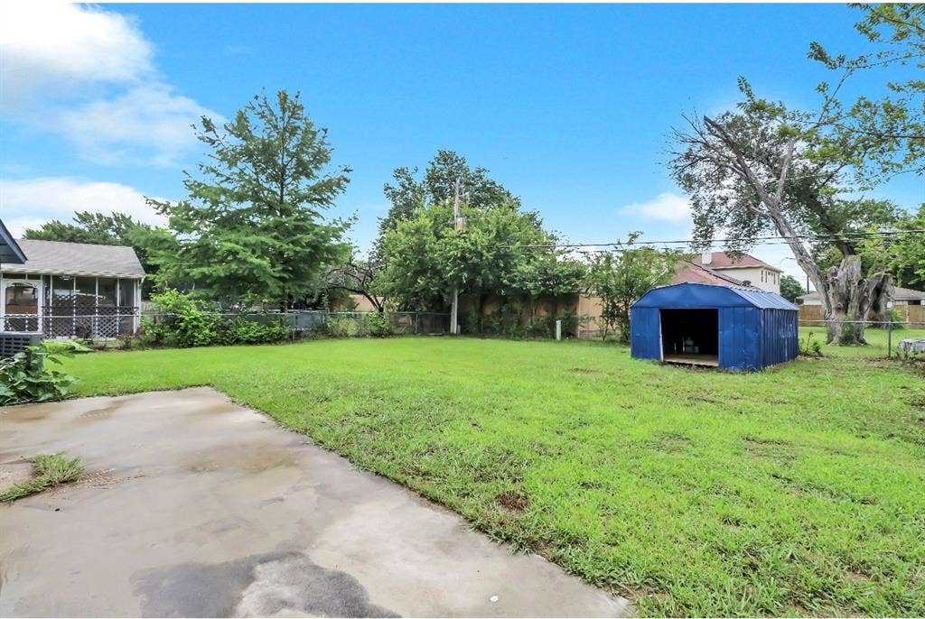 1509 California Trail, Grand Prairie, TX 75052 Expansive backyard featuring a concrete patio, a blue metal shed, and a screened porch