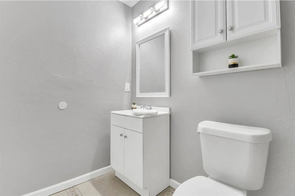 1509 California Trail, Grand Prairie, TX 75052 Bathroom featuring a white vanity with integrated sink, framed mirror, and chrome-finish light fixture