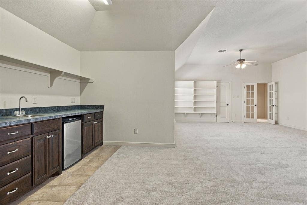 7004 Cherrybark Lane, North Richland Hills, TX 76182 Built-in wet bar with wood cabinetry, integrated mini-refrigerator, and wall-mounted shelving