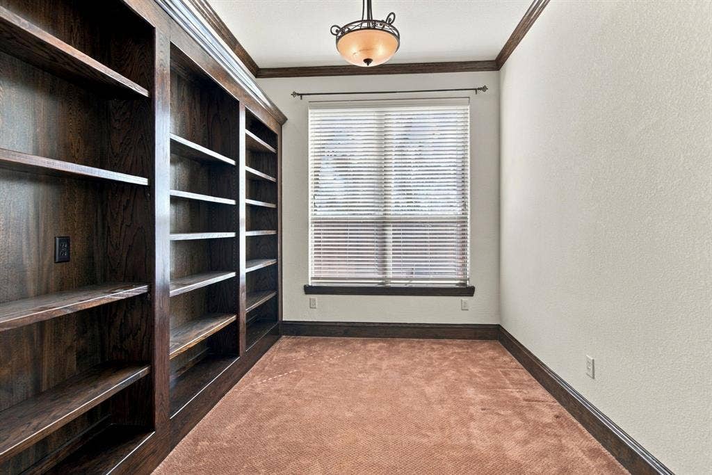 7004 Cherrybark Lane, North Richland Hills, TX 76182 Built-in wood shelving, window with blinds, recessed ceiling light fixture, crown molding, and contrasting wood trim