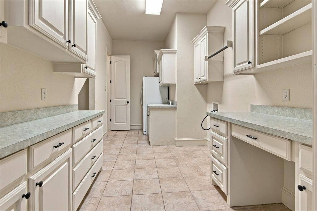7004 Cherrybark Lane, North Richland Hills, TX 76182 Spacious utility room featuring extensive built-in cabinetry, durable countertops, tiled flooring, and an integrated drying rack