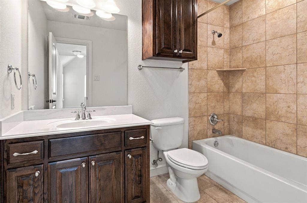 7004 Cherrybark Lane, North Richland Hills, TX 76182 Dark wood-finish vanity with white countertop, chrome fixtures, and overhead light bar