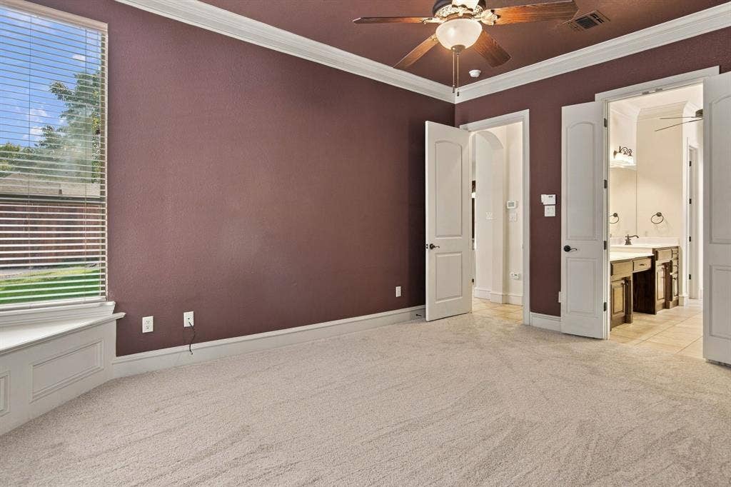 7004 Cherrybark Lane, North Richland Hills, TX 76182 Neutral-toned carpeting, bay window with integrated seating, ceiling fan with integrated lighting, crown molding, and arched doorways