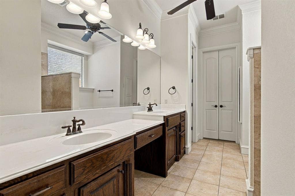 7004 Cherrybark Lane, North Richland Hills, TX 76182 Double vanity with white countertops, dark wood cabinetry, and oil-rubbed bronze fixtures