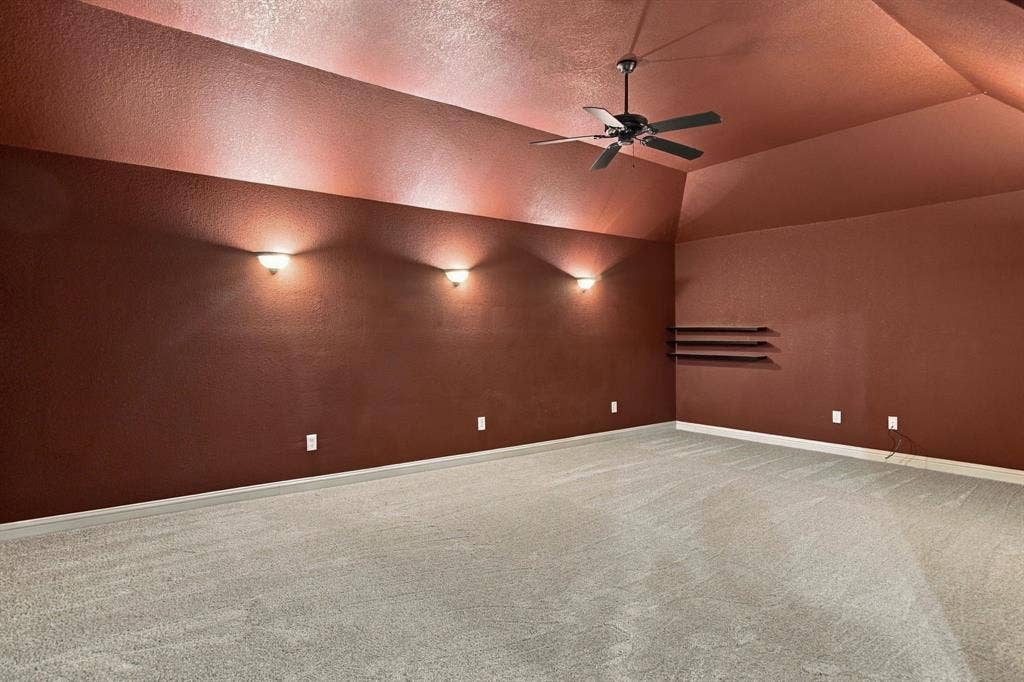 7004 Cherrybark Lane, North Richland Hills, TX 76182 Vaulted ceiling with a ceiling fan, wall-mounted sconces, built-in shelving, and light gray carpet