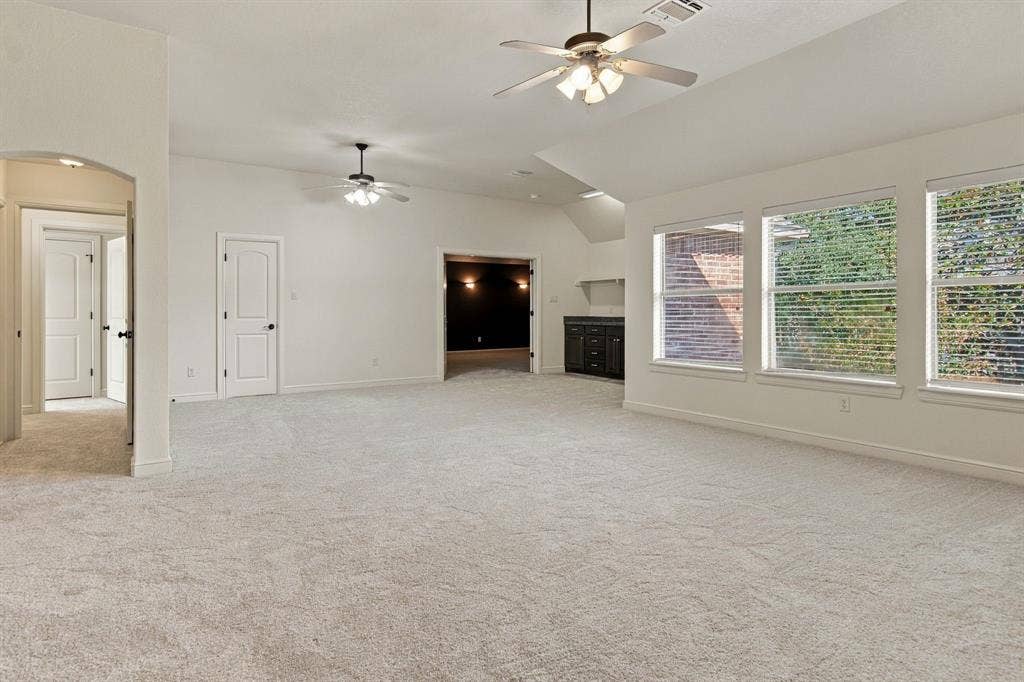 7004 Cherrybark Lane, North Richland Hills, TX 76182 Spacious room with light-colored carpeting, multiple windows with blinds, and two ceiling fans