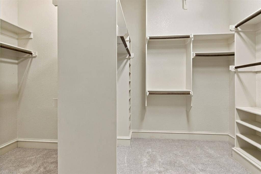 7004 Cherrybark Lane, North Richland Hills, TX 76182 Spacious walk-in closet with multiple built-in shelving units, integrated hanging rods, and light-colored carpeting