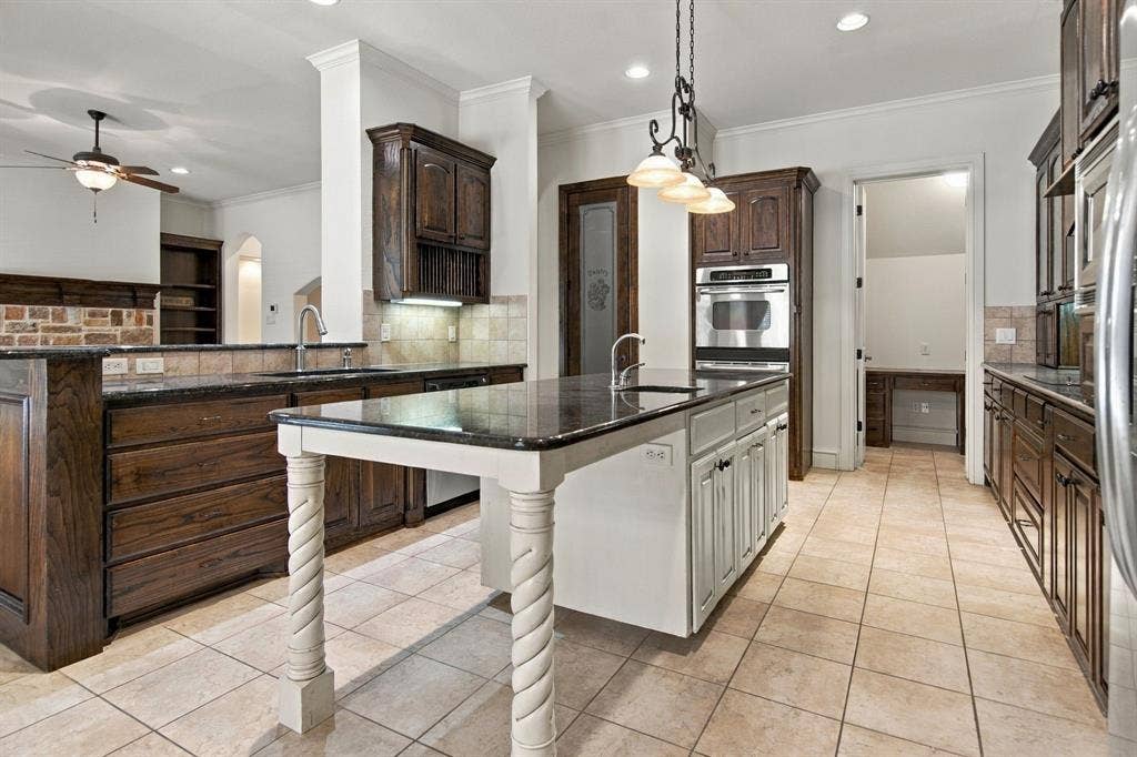 7004 Cherrybark Lane, North Richland Hills, TX 76182 Kitchen featuring dark wood cabinetry, a central island with carved legs, stainless steel built-in appliances, and tile flooring