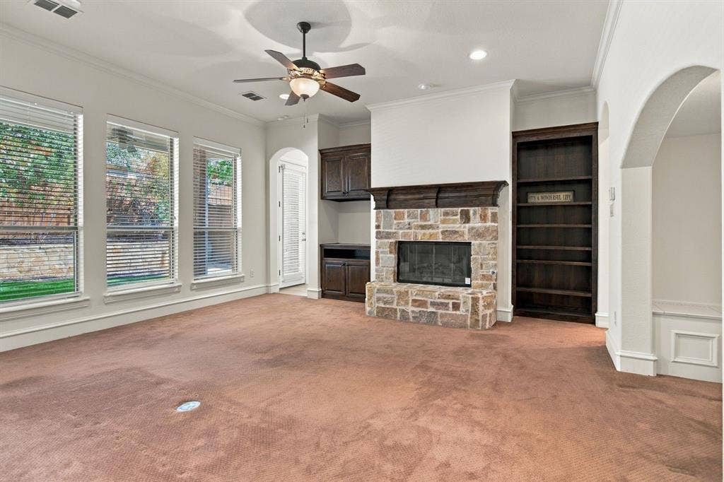 7004 Cherrybark Lane, North Richland Hills, TX 76182 Stone-faced fireplace with a wood mantle, built-in shelving, dark wood-finish cabinetry, and multiple windows