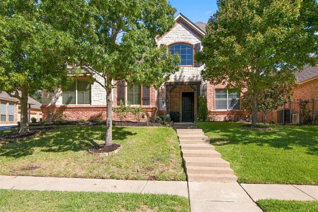 7004 Cherrybark Lane, North Richland Hills, TX 76182 Brick and stone facade with arched window, covered entryway, and mature trees
