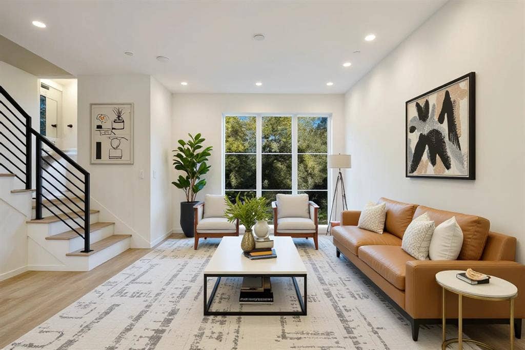 4811 Denton Drive, #201, Dallas, TX 75219 Recessed lighting illuminates the open-concept space, featuring wood-finish flooring and a staircase with contemporary black railings