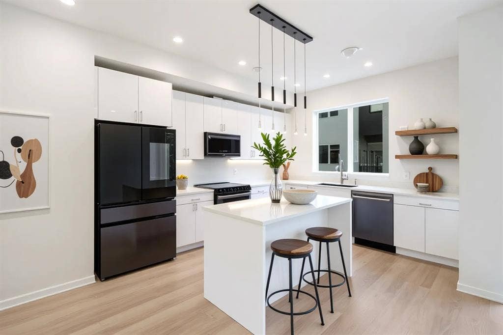 4811 Denton Drive, #201, Dallas, TX 75219 Contemporary kitchen featuring light wood-finish flooring, white cabinetry, dark-finish appliances, and a central island with pendant lighting