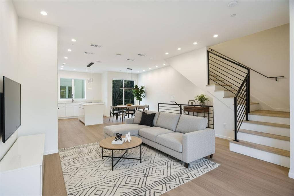 4811 Denton Drive, #201, Dallas, TX 75219 Open-concept living space featuring wood-finish flooring, recessed lighting, and a modern staircase with black metal railings